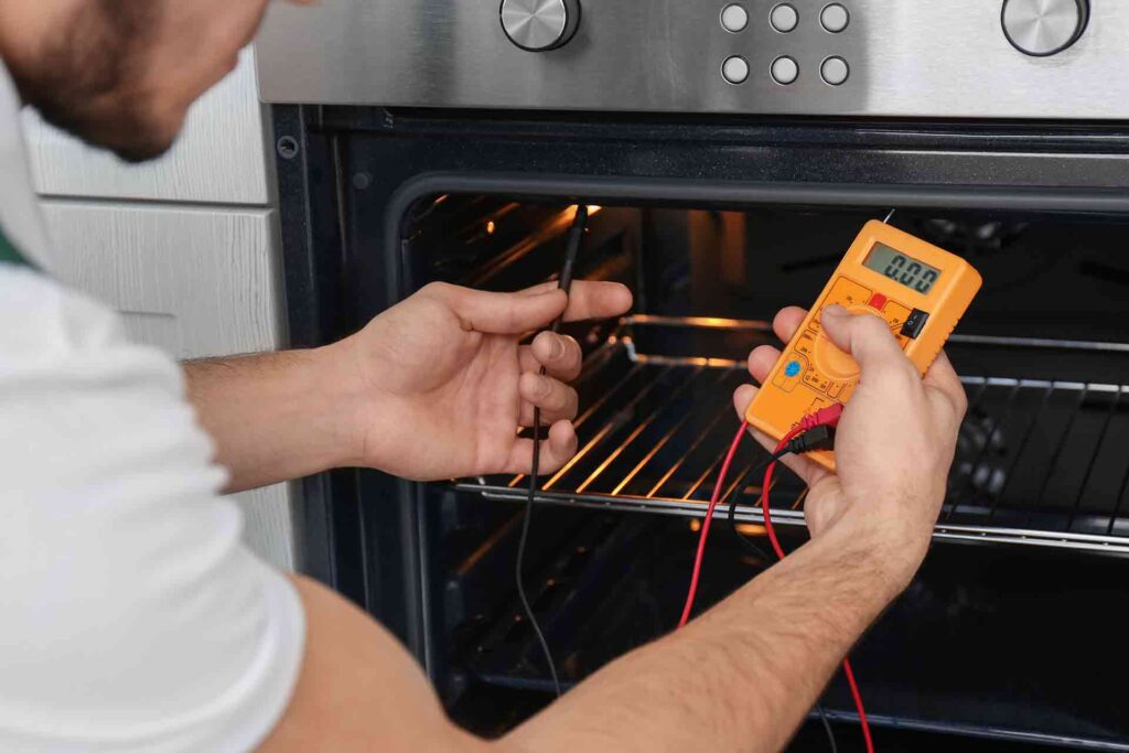 man testing oven Sensor with a Multimeter
