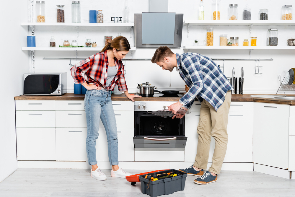 technician repairing oven with customer