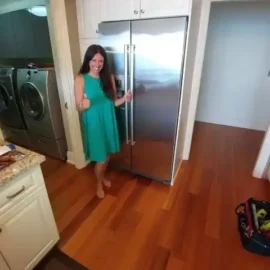 Smiling client beside repaired built in fridge